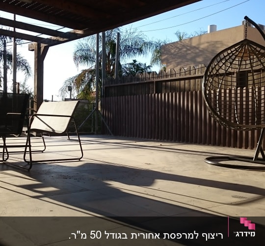 מרפסת עם רצפת בטון, גדר עץ וכיסאות מתכת